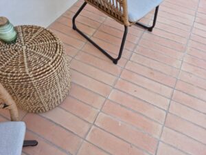 Suelo de barro cocido exterior con silla y mesa de rattan en terraza